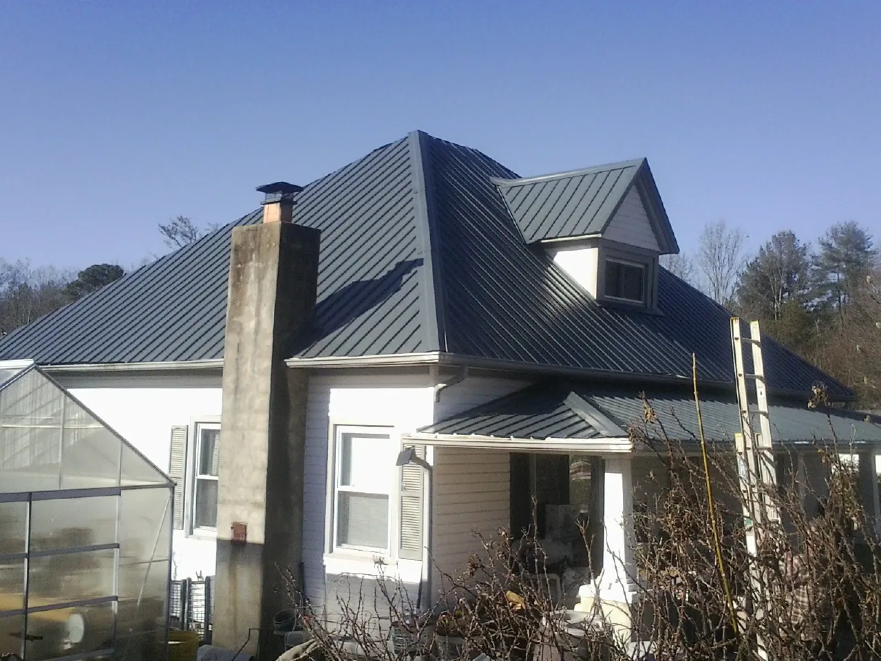 Dark blue standing seam metal roof on a white farmhouse with dormer — Slate & Tile Roof Repair by Roofing Brothers in South Tamworth