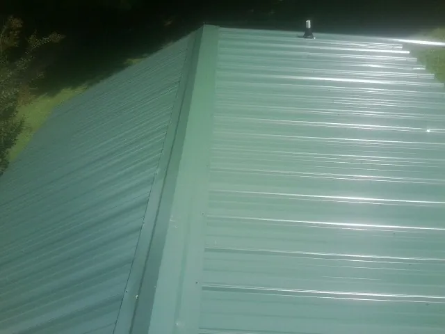 New green metal panels meeting at the ridge of a roof — Flat Roof Repair work by our crew in South Tamworth