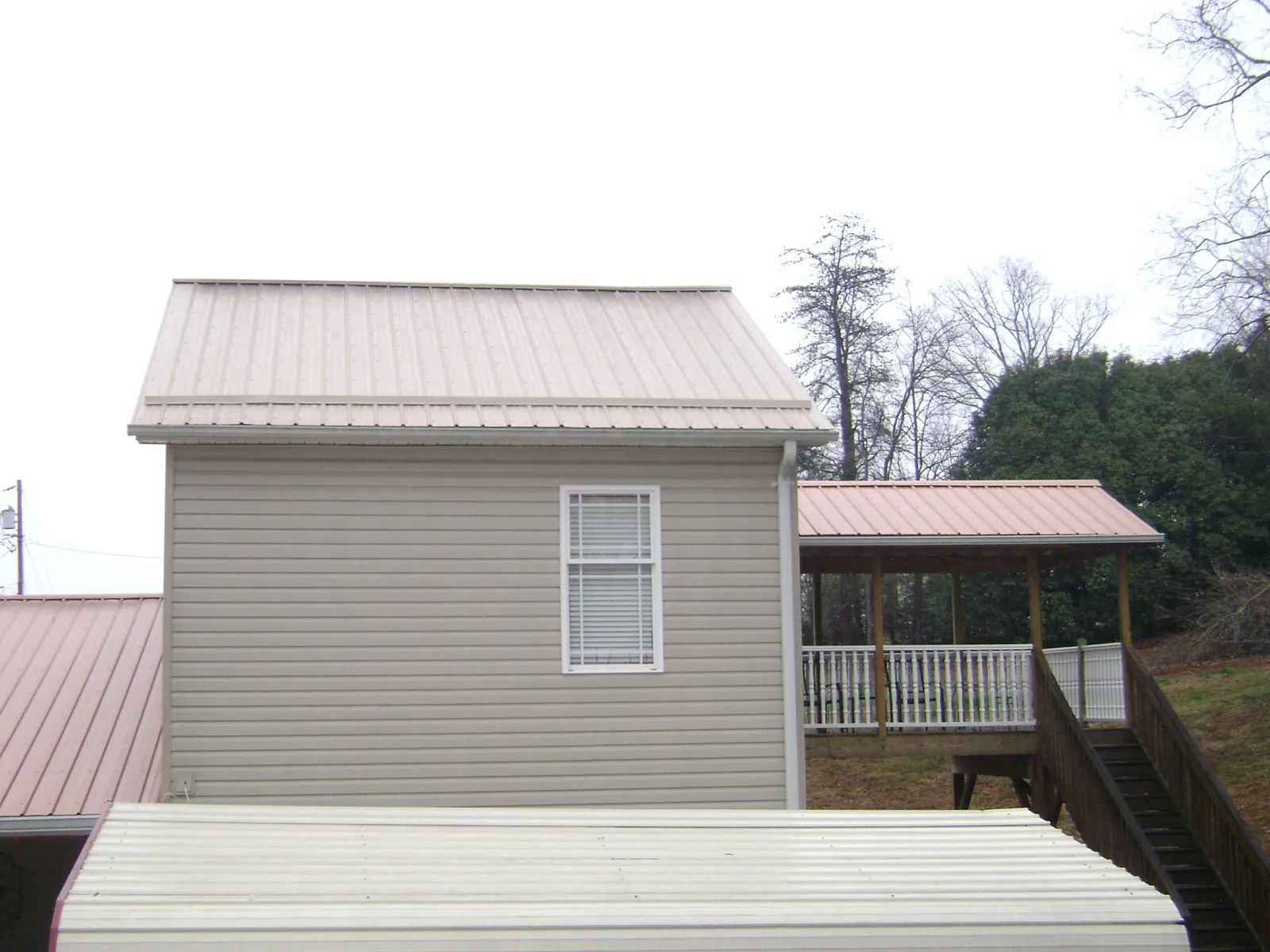 Tan metal roofs on a two story addition and attached porch, from a Roof Replacement job in South Tamworth